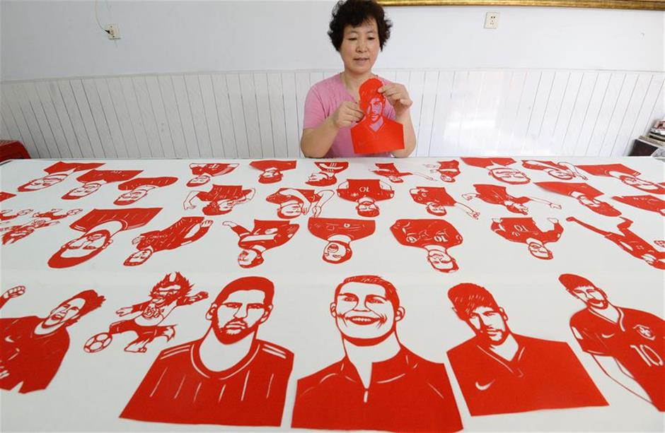 Craftswoman makes paper-cutting works to greet World Cup