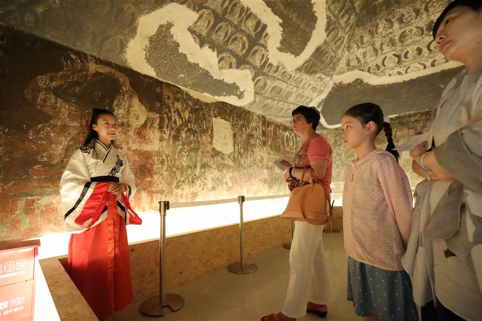 Dunhuang students fly in town to guide visitors at grotto art exhibition