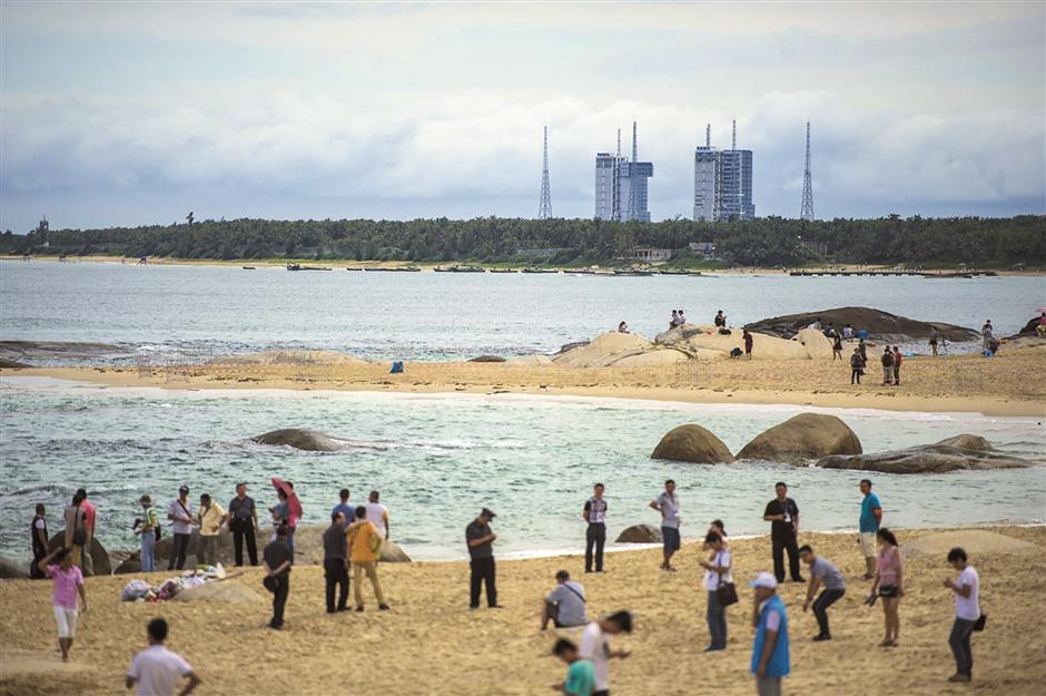 On a tropical island wonderland, tourists on beaches gaze skyward